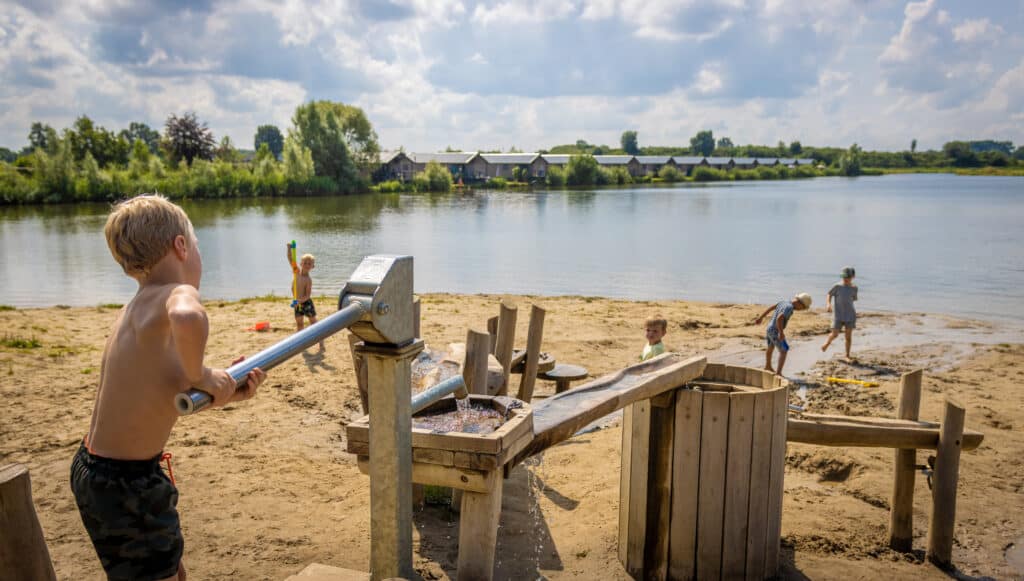 Kinderen spelen op het interactieve speelveld aan de waterkant van het Familievakantiepark Krieghuusbelten in Raalte in Overijssel