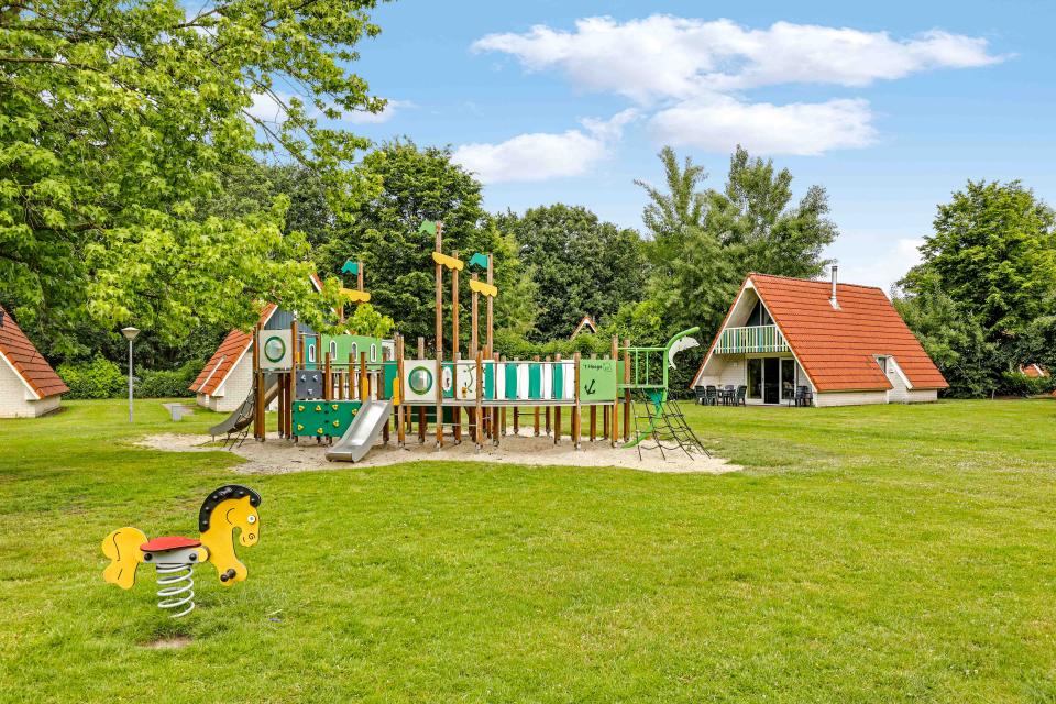 Speeltuin met op de achtergrond een kinderbungalow op Vakantiepark 't Hooge Holt in Gramsbergen in Overijssel